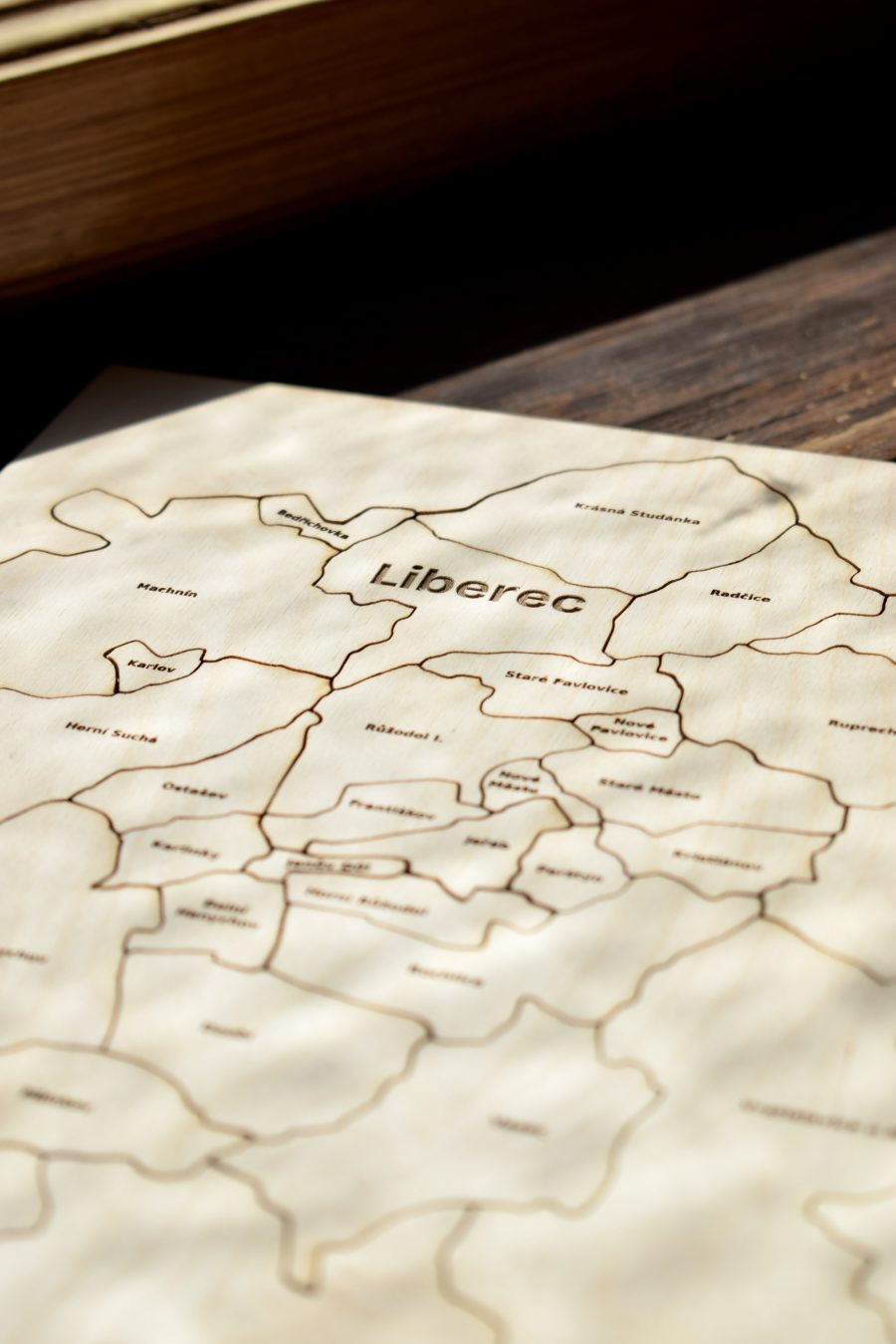 Detail dílků puzzle zblízka – čitelné názvy čtvrtí Machnín, Karlov, Krásná Studánka a Staré Pavlovice.